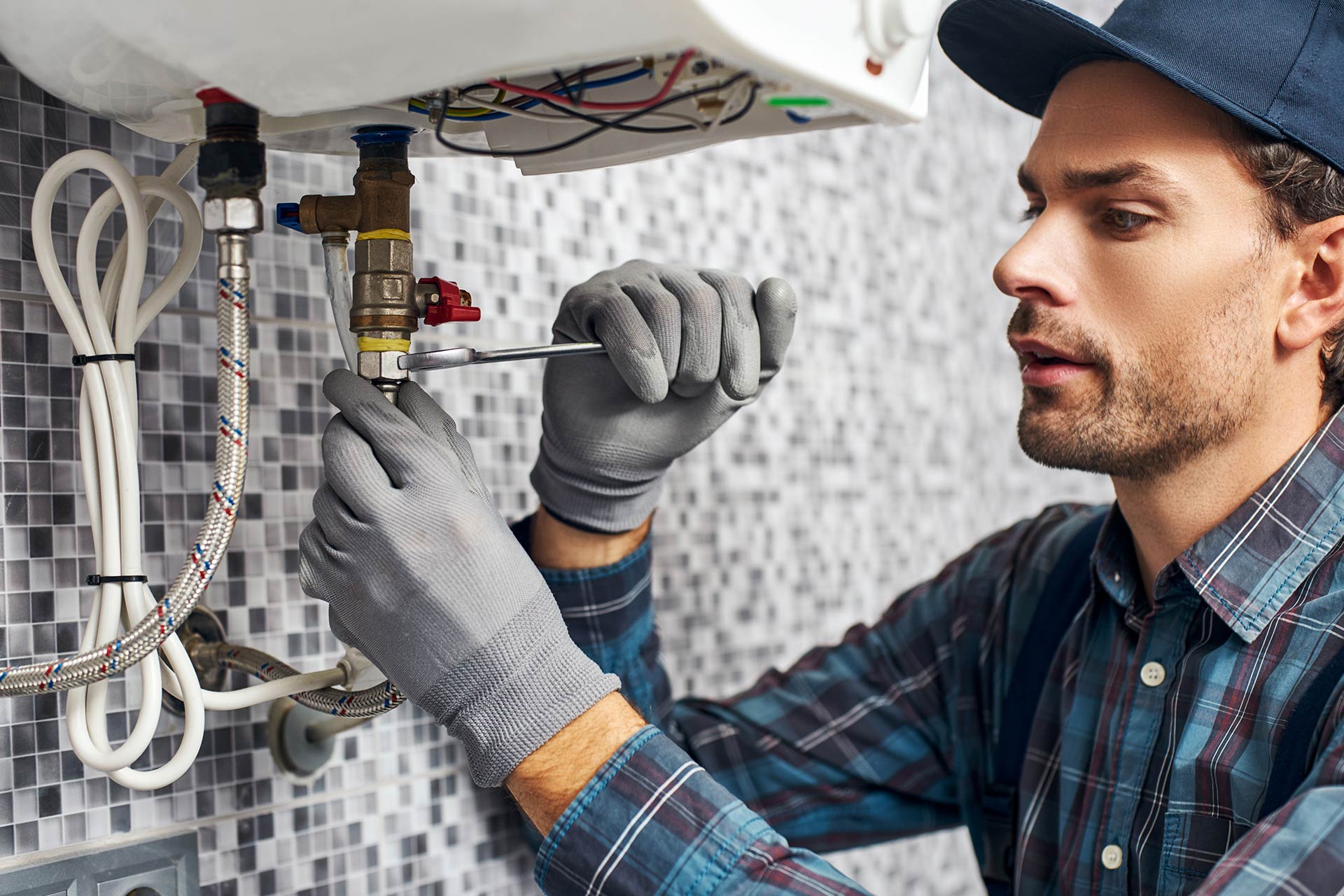 A man in a hat and gloves repairing a water heater from Sp comforts